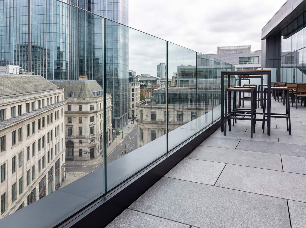 Fully frameless glass balustrade with a silver base channel installed on a modern city balcony, providing safety without obstructing urban views
