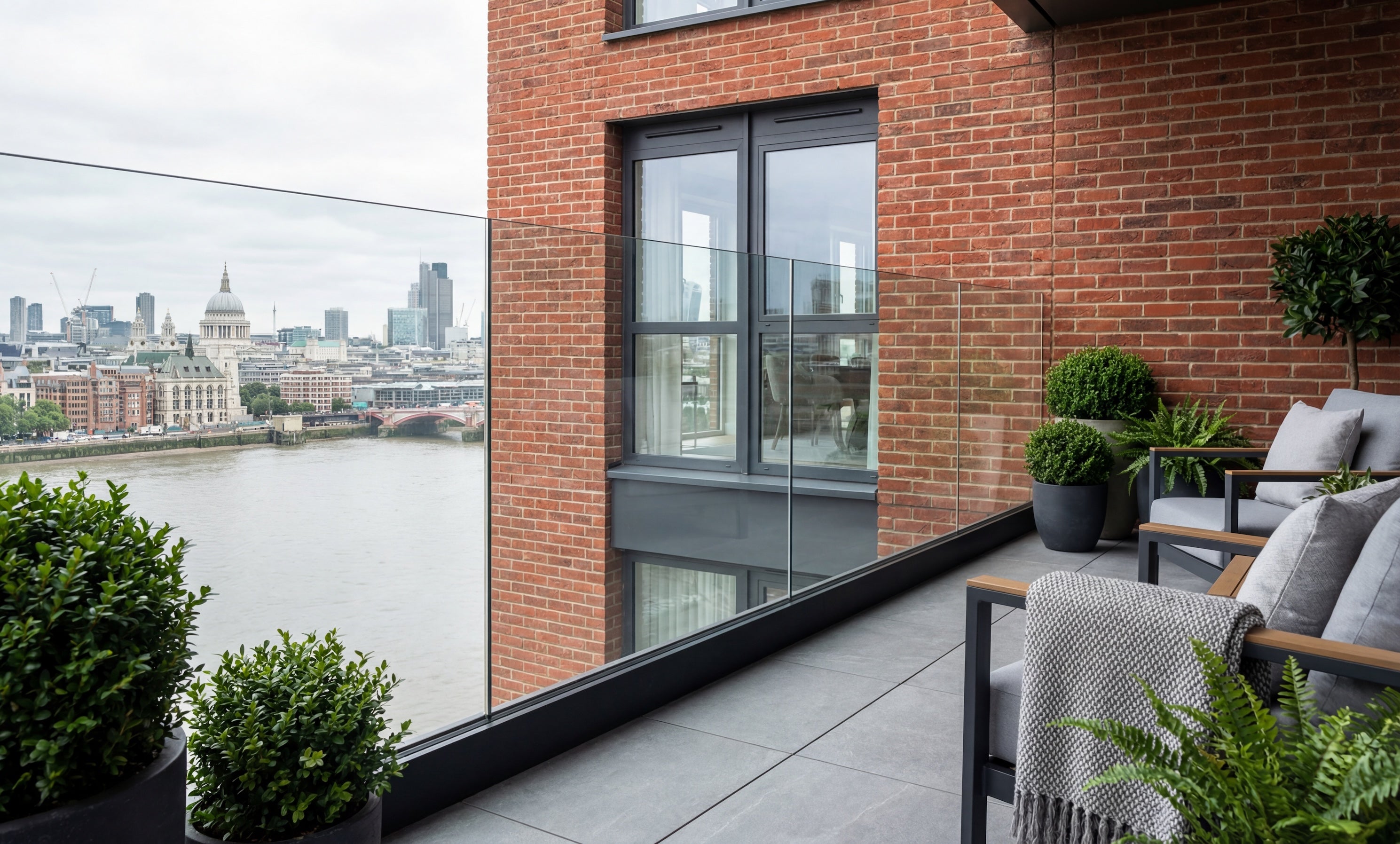 Fully frameless black glass balustrade installed on a London balcony overlooking the River Thames