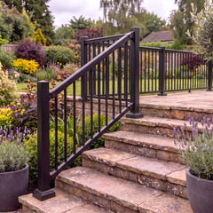 Black aluminium balustrade running down stone garden steps and continuing along a level terrace, with angled stair rails meeting a shared corner post