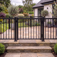 Black aluminium balustrade gate installed closed between main posts at the top of stone garden steps