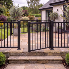 Black aluminium balustrade gate shown open on its hinges at the top of garden steps, self-closing gate for decking and patios
